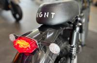 Heckansicht eines Motorrads mit leuchtender Rückleuchte und schwarzem Sitz.