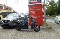 Elektroroller und dunkles Auto vor dem Autohaus Richter & Zech.