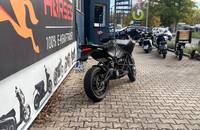 Schwarzes Adventure-Motorrad (ZERO) auf einem gepflasterten Parkplatz vor einem Autohaus.