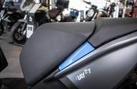 Nahaufnahme des hinteren Motorradteils mit Sitz und blauem Akzentstreifen.