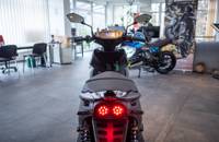 Heckansicht eines grauen E-Motorrads in einem Autohaus.