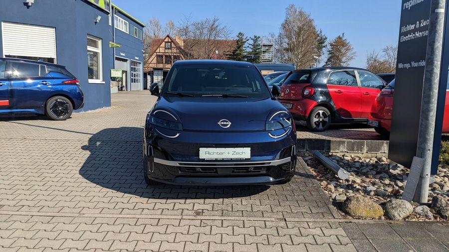 Dunkelblauer Nissan Micra EV vor dem Autohaus Richter & Zech.