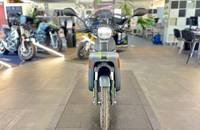Frontalansicht eines elektrischen Motorrollers in mattem Metallic-Titan, ausgestellt in einem Showroom.