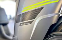 Nahaufnahme der Seitenverkleidung eines Elektrofahrzeugs in mattem Grau. Ein gelber Akzentstreifen und das eS3 evolution