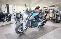 Silbernes E-Motorrad in Dreiviertelansicht in einem Showroom.