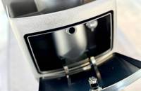 Nahaufnahme des geöffneten Ladeanschlussbereichs eines Elektrofahrzeugs, der einen sichtbaren Lade-Stecker zeigt.