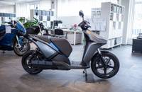 Seitenansicht eines grauen Elektrorollers (RAY 7.7) in einem Showroom.