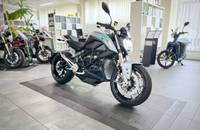 Eine silberne Elektro-Motorrad ist in einer Dreiviertelansicht auf einem Verkaufsboden ausgestellt.