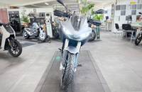 Frontalansicht eines silbernen Elektro-Adventure-Motorrads in einem hellen Showroom.
