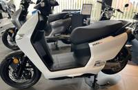 Weiße Scooter in Dreiviertelansicht, geparkt in einem Autohaus.