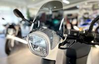 Nahaufnahme des Scheinwerfers und des Windschilds eines weißen Elektroscooters.