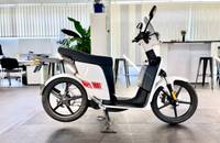 Seitenansicht eines weißen Elektro-Rollers (ANDERE eS3 EVO) in einem hellen Showroom.
