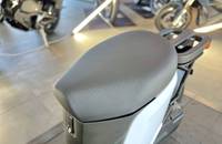 Nahaufnahme des grauen Sitzes und des weißen Heckbereichs eines Elektroscooters in einem Showroom.