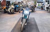 Schwarzes E-Motorrad in einer Ausstellungshalle, aufgenommen aus der Frontansicht.