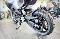 Seitenansicht eines silbernen E-Motorrads, die das große Rad und den unteren Rahmenbereich detailliert zeigt.