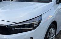 Nahaufnahme der weißen Frontpartie eines Opel Corsa mit Scheinwerfer und Rad.