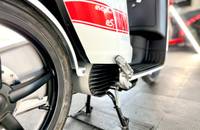 Nahaufnahme des linken Rades und des Motorbereichs eines E-Scooters. Man sieht die Seitenverkleidung und die Kühlrippen.
