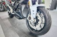 Silbernes E-Motorrad im Profil mit Fokus auf das Vorderrad und die Bremsen.