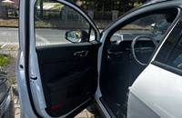 KIA Sportage mit geöffneter Fahrertür, Innenraum und Armaturenbrett sichtbar.
