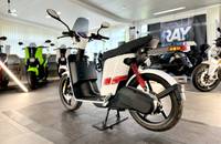 Ein weißer elektrischer Roller (ANDERE eS3 EVO) wird in einem Showroom aufgestellt.