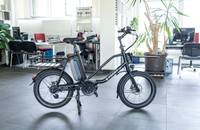 Schwarzes E-Lastenrad (E-PACKR) in Innenräumen eines Autohauses.