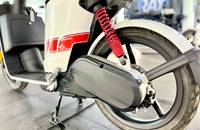 Detailansicht des Hinterrads, der Federung und des Motorgehäuses eines weißen E-Scooters.