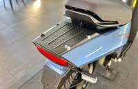 Heckansicht eines hellblauen E-Scooters mit Heckleuchten und Gepäckträger.
