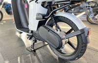Nahaufnahme des Hinterrads und der Federung eines weißen E-Scooters. Die Batterie ist sichtbar.