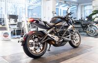 Schwarzes Motorrad mit goldenen Felgen in einem gut beleuchteten Autohaus-Showroom.