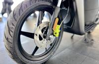 Nahaufnahme des Hinterrads eines Elektrofahrzeugs mit breitem Reifen, Bremsscheibe und Federbein.