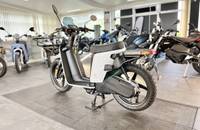Seitenansicht eines modernen, elektrischen Scooters in Weiß und Schwarz, geparkt in einer Halle.