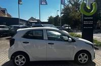 Seitenansicht eines weißen KIA Picanto, geparkt vor dem Autohaus Richter & Zech.