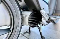 Nahaufnahme des Hinterrads und des Motorbereichs eines Elektrofahrzeugs. Man sieht die Reifenflanke und die lamellierte