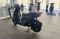 Seitenansicht eines grauen elektrischen Motorrollers in einem Showroom.