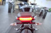 Heckansicht eines Motorrads mit leuchtendem Rücklicht in einem Showroom.