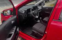Innenraumansicht eines roten KIA Picanto mit geöffneter Fahrertür. Sicht auf Cockpit und Sitze.