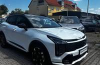 Frontansicht eines weißen KIA Sportage, geparkt vor einem Autohaus.