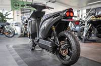 Schwarzes E-Motorrad in Seitenansicht in einem Showroom.