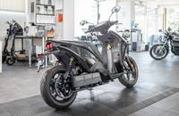 Seitenansicht eines dunklen Elektrorollers in einem Autohaus.