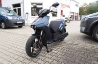 Seitenansicht des dunkelblauen elektrischen Rollers RAY 7.7 vor einem Autohaus.