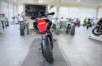 Ein silbernes E-Motorrad wird in einem hellen Showroom von hinten aufgenommen.