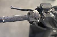 Nahaufnahme des Lenkergriffs und der Bedienelemente eines Motorrollers.