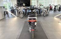 Mehrere E-Scooter in einem Showroom. Im Vordergrund ist ein weißer Roller von hinten zu sehen.