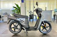 Seitenansicht eines grauen, elektrischen Scooters (Askoll) in einem hellen Showroom.