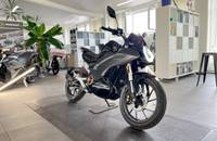 Schwarzes Motorrad (VMOTO STASH) in einem Autohaus-Showroom.