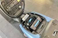 Offene Motorhaube mit sichtbaren Batterien und elektrischen Komponenten.
