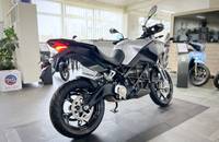 Ein silbernes Adventure-Motorrad steht in einem hellen Showroom.