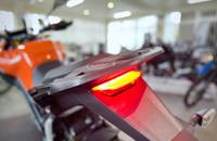 Nahaufnahme des roten Rücklichts und des orangefarbenen Heckbereichs eines E-Scooters.