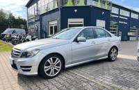 Ein silberner Mercedes-Benz C180 steht vor dem Autohaus Richter & Zech.