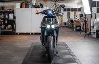 Frontalansicht eines schwarzen elektrischen Motorrollers in einem Showroom.
